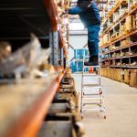 A man standing on a ladder in a warehouse