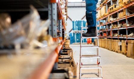 A man standing on a ladder in a warehouse
